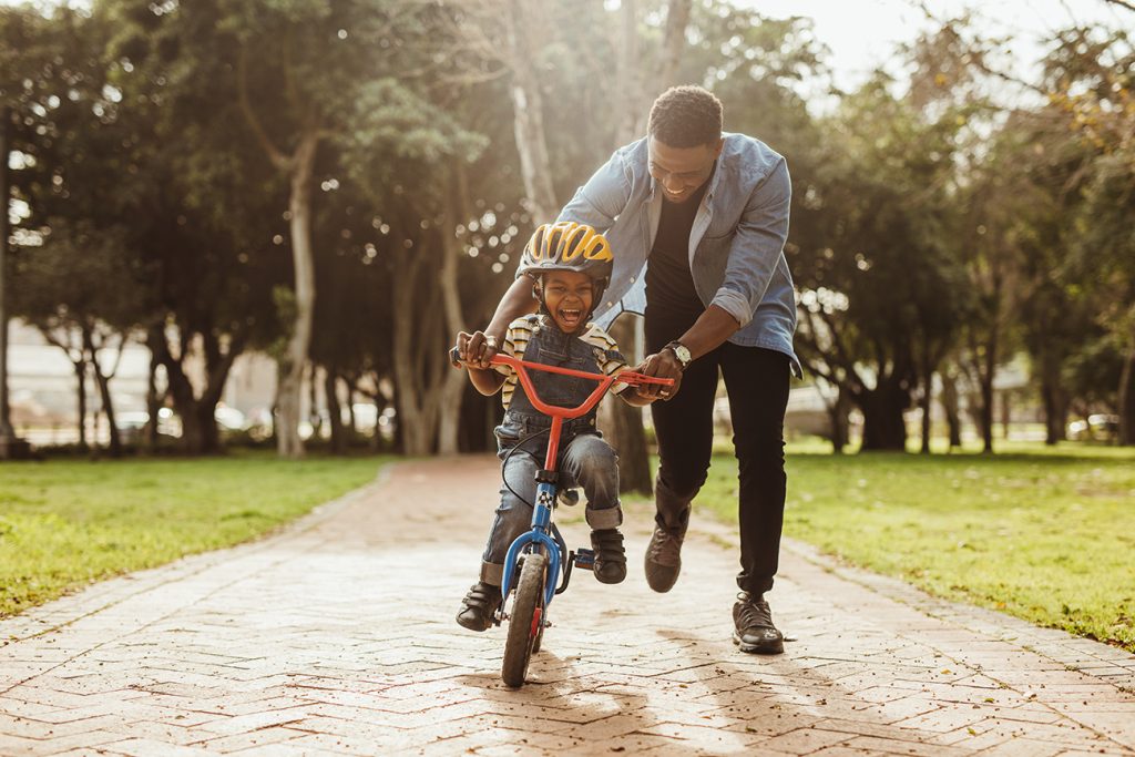 Boy learning to ride a bicycle with his father in Westlake Park in the Energy Corridor..