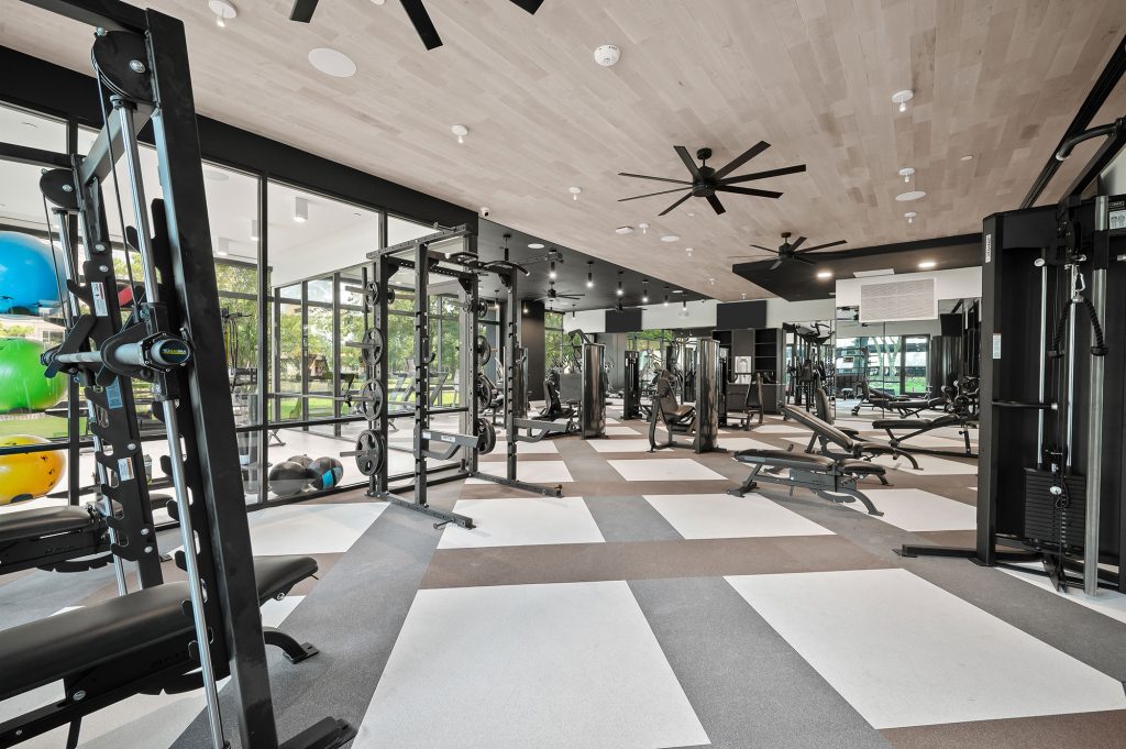 The fitness center at The Watt apartments with various weight machines and a yoga room.