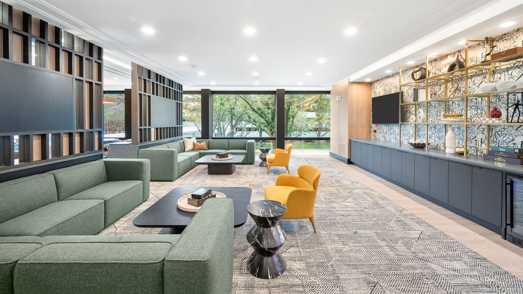 The luxurious clubroom with large sofas, tvs, and wine fridge in The Watt luxury apartments..