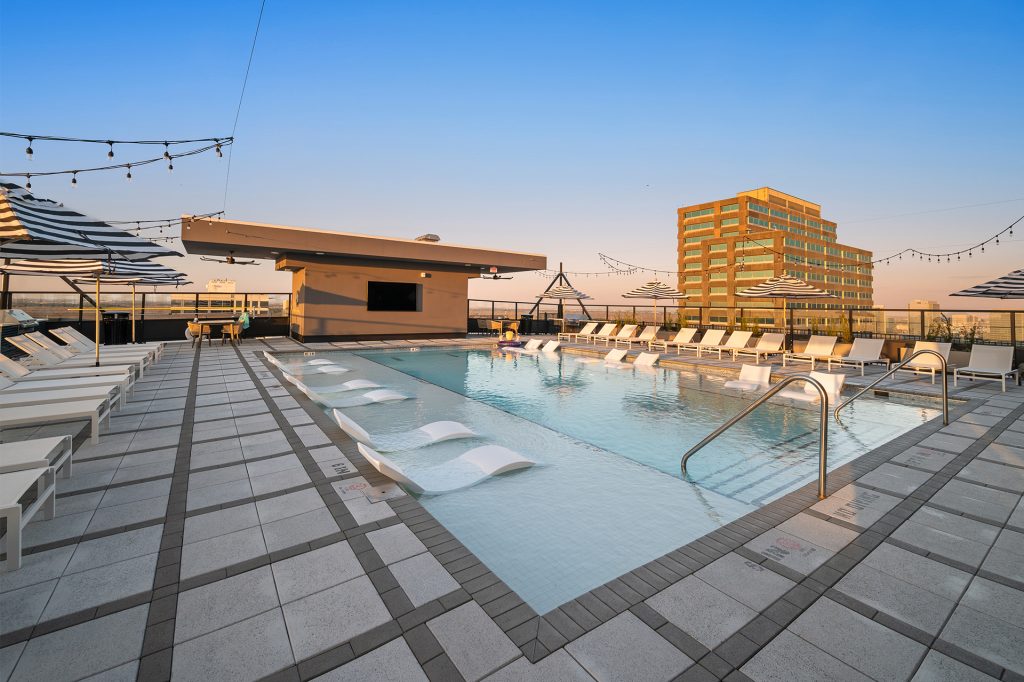 The Watt rooftop pool with in-water loungers, lounge chairs, and umbrellas
