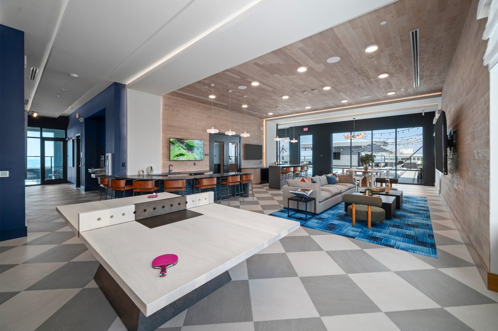Rooftop clubroom with ping-pong table, seating area, bar area, and a view of the rooftop pool